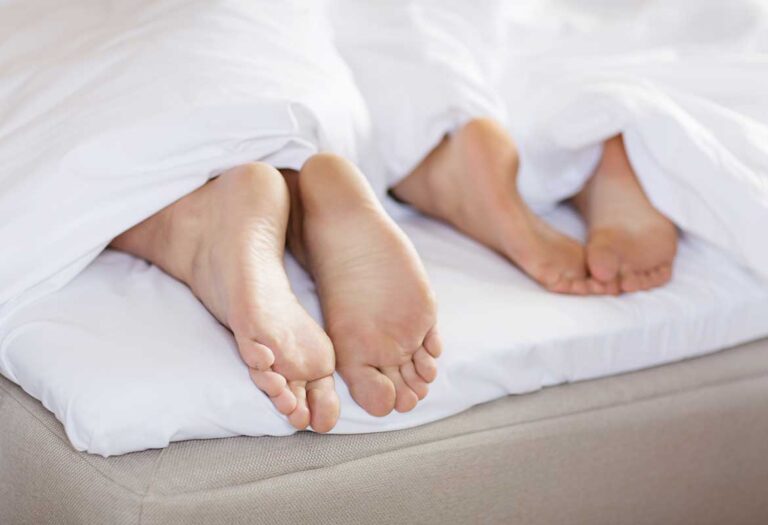 Fötter undertäcke i säng